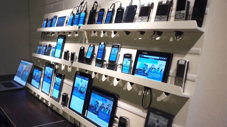 three shelves of different devices - phones, tablets, laptops, etc